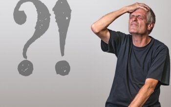 Mężczyzna trzymający się za głowę dumający nad słowami w języku francuskim.